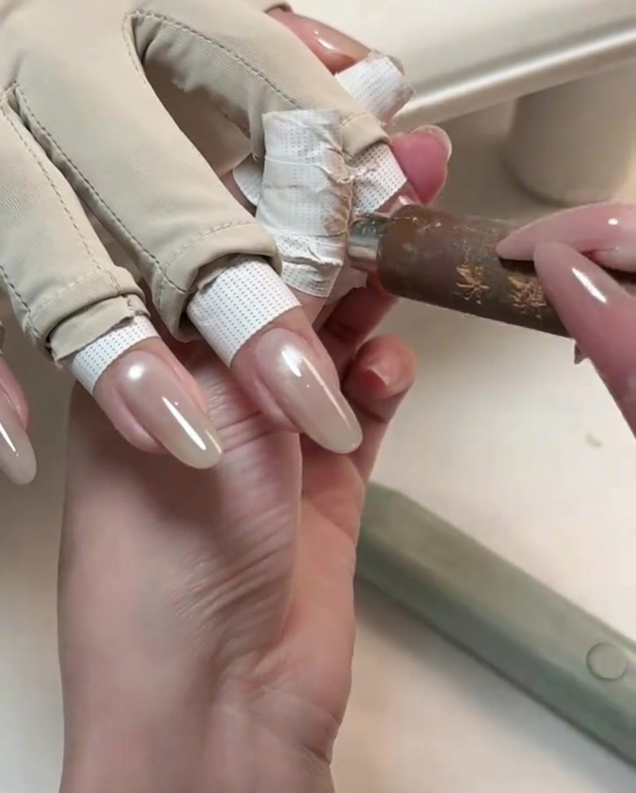 Narzędzie magnetyczne trzymane blisko błyszczącego, wymodelowanego paznokcia w celu wyciągnięcia lśniącej linii światła cat-eye.