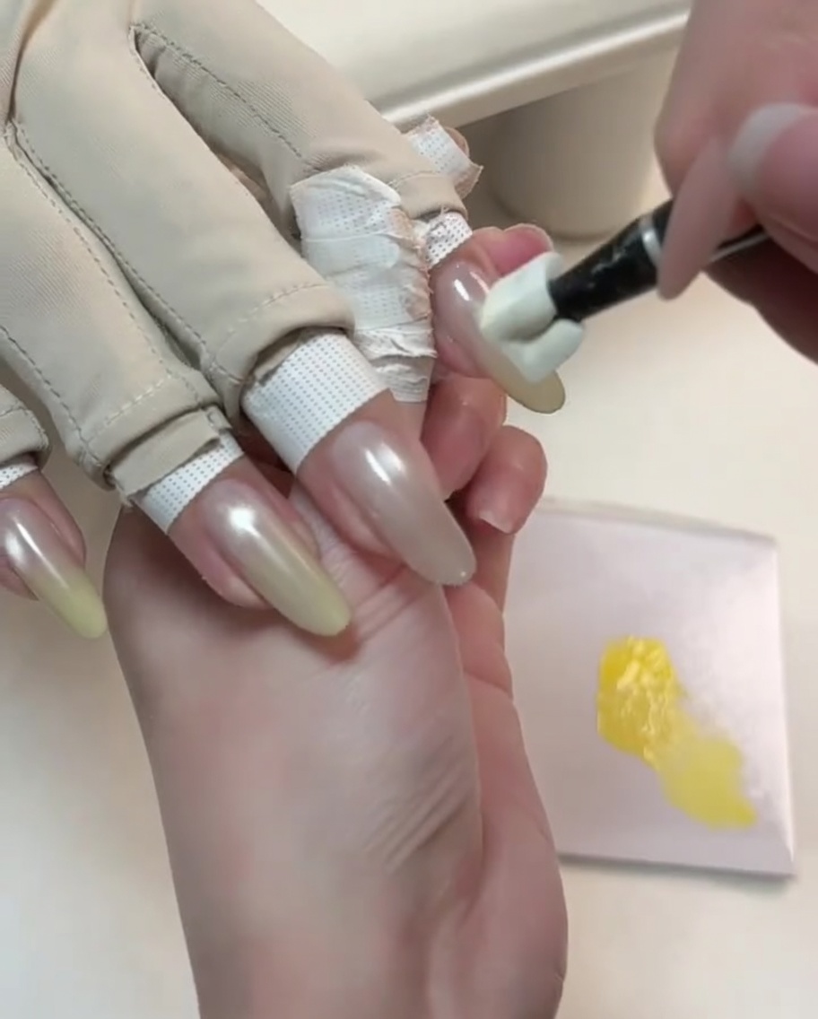 Specjalistyczne narzędzie wklepujące żółty żel na końcówkę paznokcia nude cat-eye w celu rozpoczęcia gradientu.