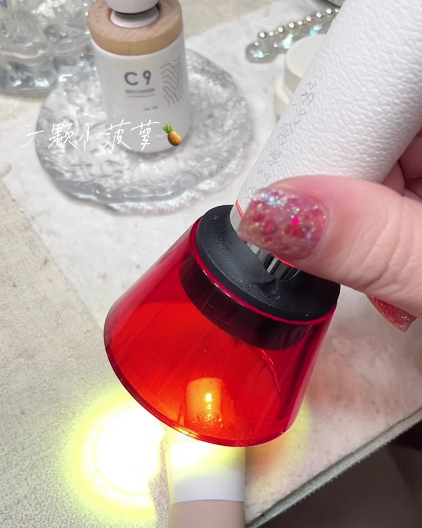 Ręczna czerwona mini lampa UV utwardzająca paznokieć na palcu.