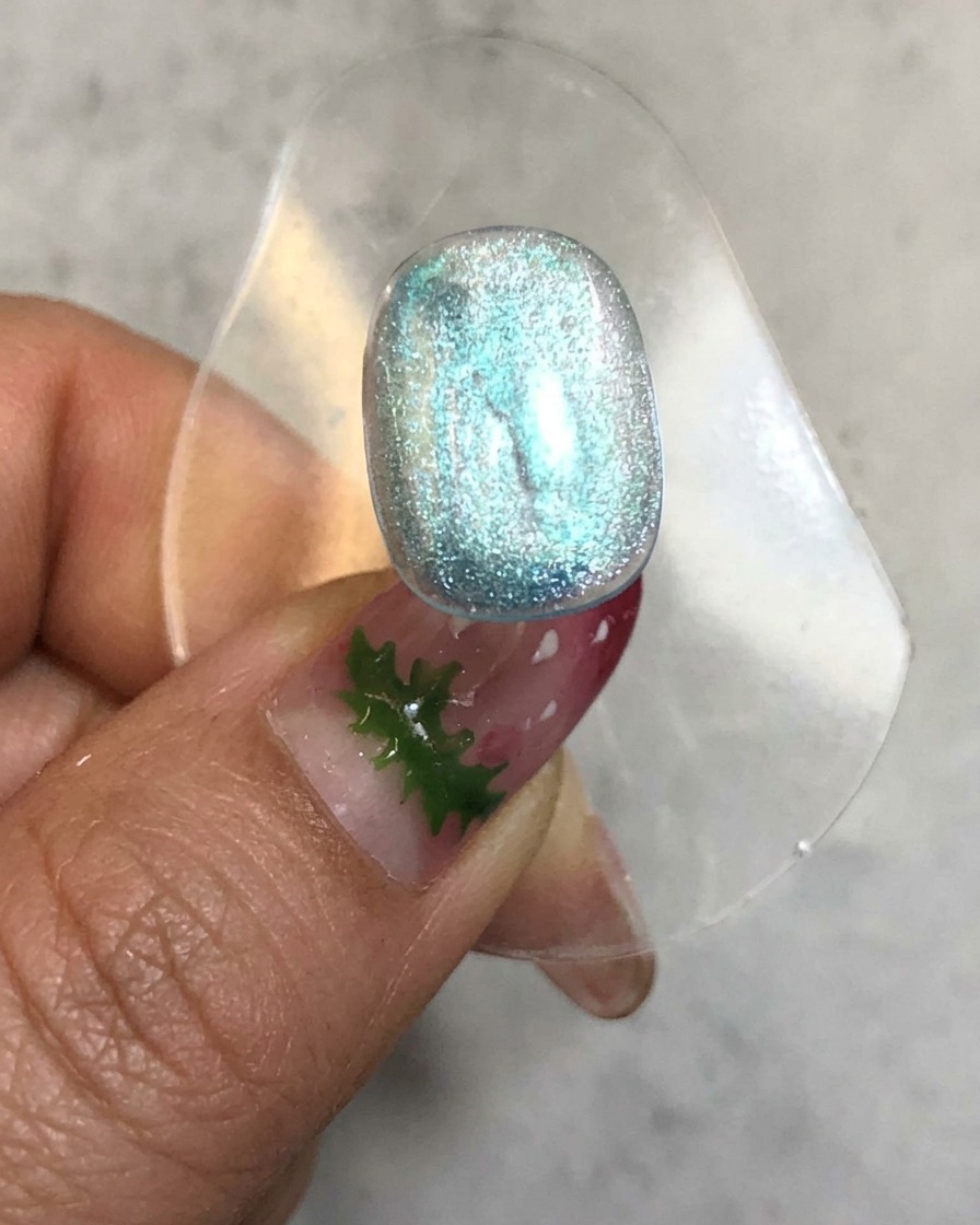 Ein Nagel befindet sich in einer Aushärtungslampe mit glühendem Licht, das um die transluzente blaue Geloberfläche herum austritt.
