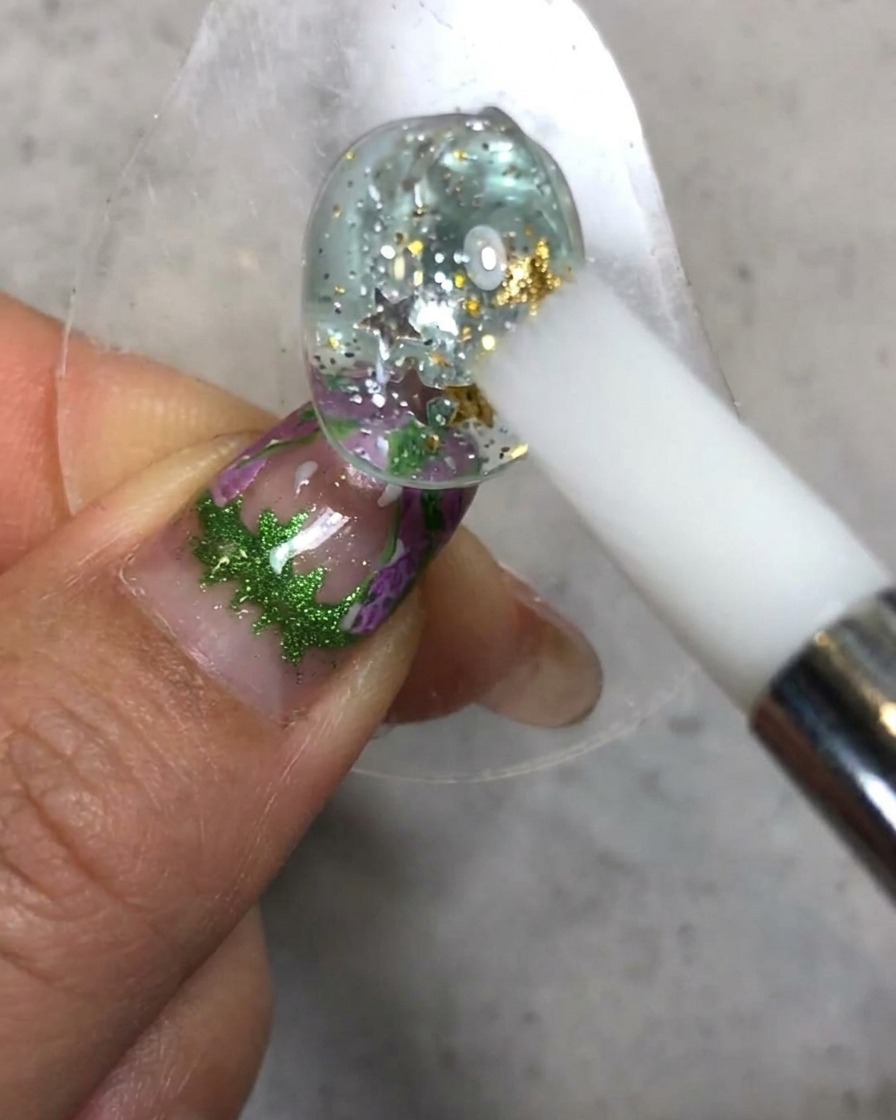 Ein weisser Silikonstift formt und glättet die weiche Candy-Gel-Textur auf der Oberseite der verzierten Nageloberfläche.