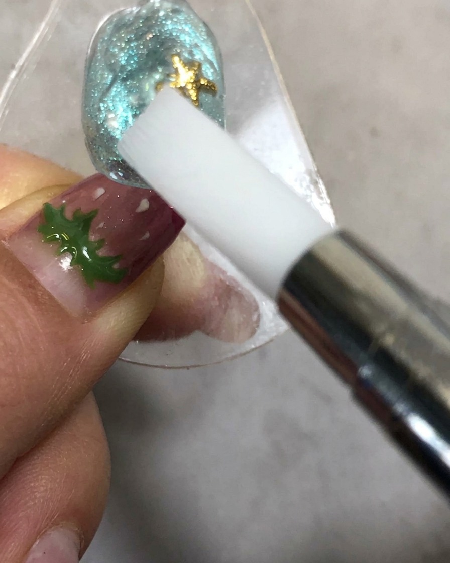 Eine Hand hält ein Silikon-Formungswerkzeug in der Nähe eines Nagels unter einer Aushärtungslampe.
