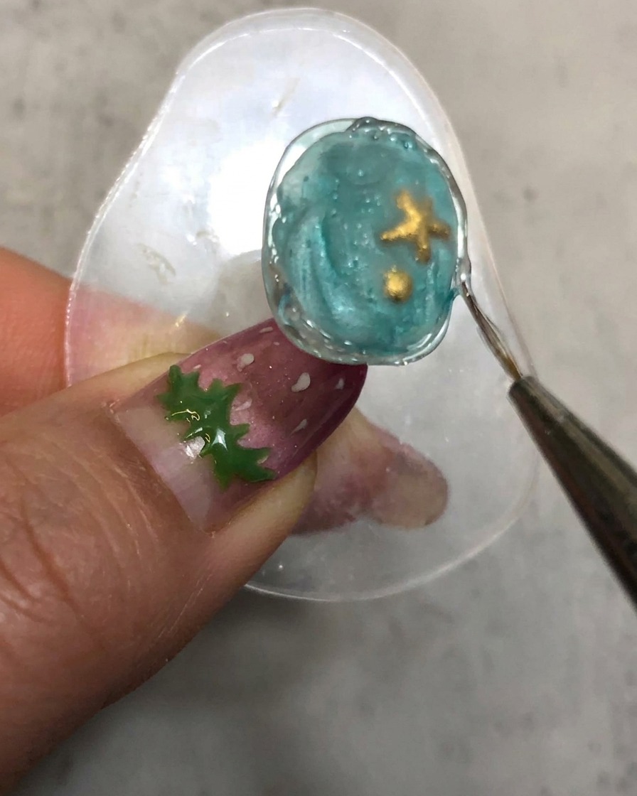 Ein Detailpinsel zieht entlang der ausgehärteten, strukturierten Styling-Gel-Umrandung des Nagels nach.