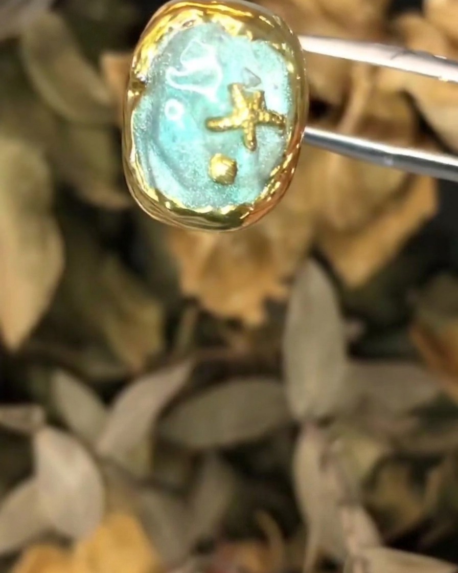 Eine Pinzette hält das strukturierte Ozean-Nail-Art-Stück während des finalen Auftrags der Schichten.