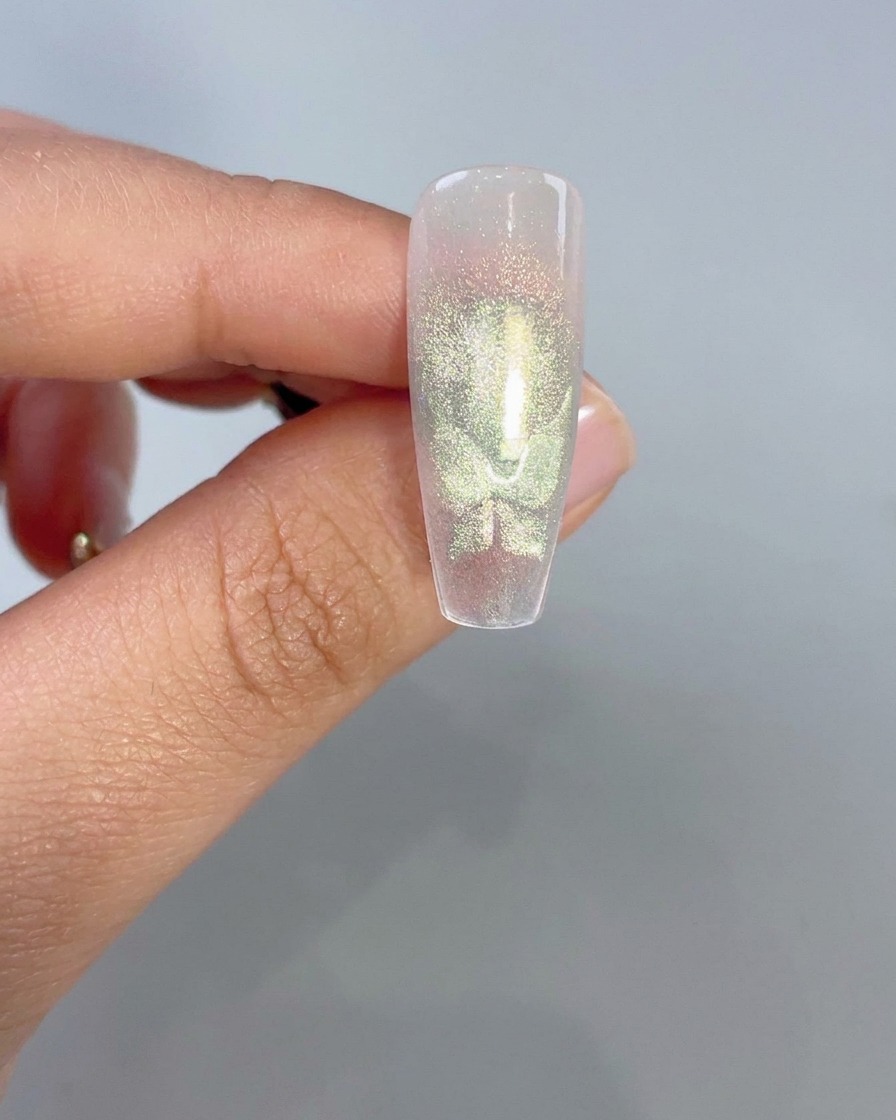 Zbliżenie na przezroczysty tips ukazujący świecące zielone kształty skrzydeł motyla cat-eye po aktywacji magnetycznej.