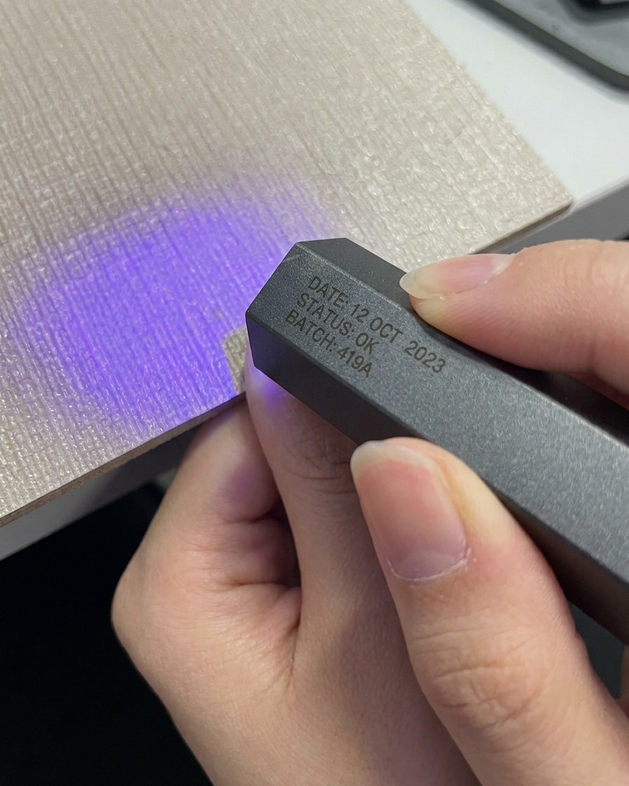 Dłoń umieszczająca kciuk pod kompaktową, szarą, przenośną lampą UV LED.