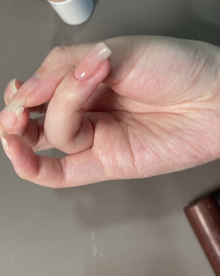 Eine Hand wird für die finale Aushärtung unter eine UV-Lampe positioniert.