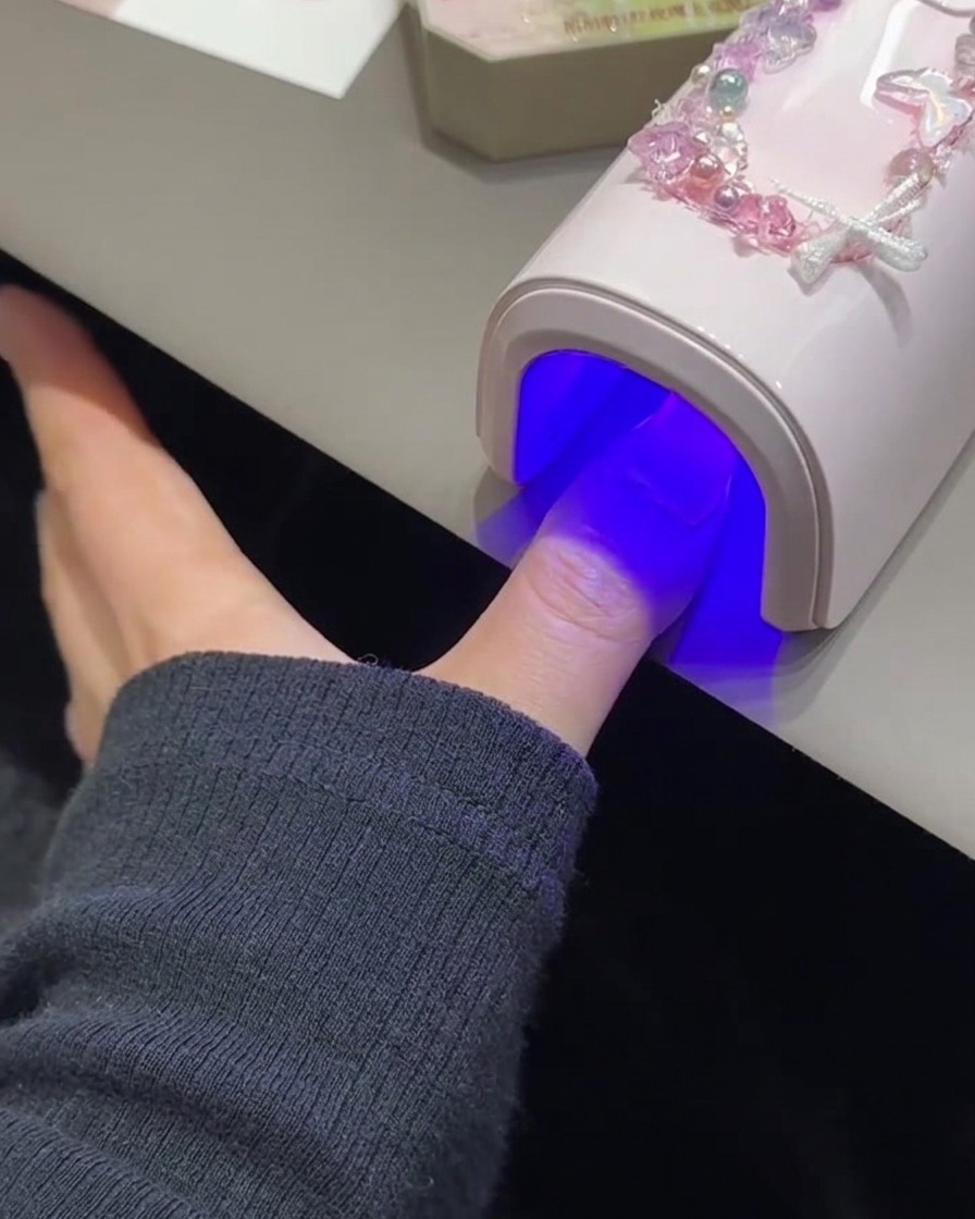 Paznokieć utwardzający się pod różową lampą UV/LED.