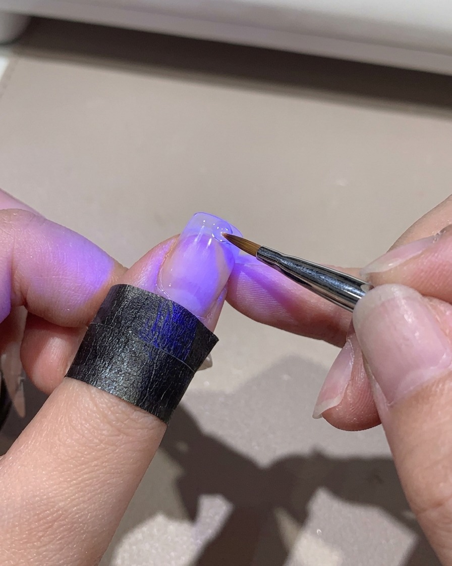 Mini lampa UV utwardzająca gradientową końcówkę paznokcia trzymaną w dłoni.