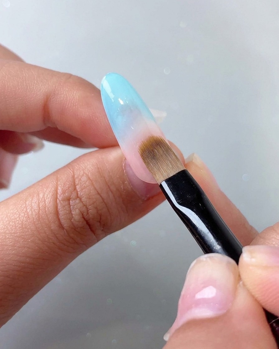 Pędzel do wklepywania blendujący niebieski gradient na górnej, różowawej części paznokcia.