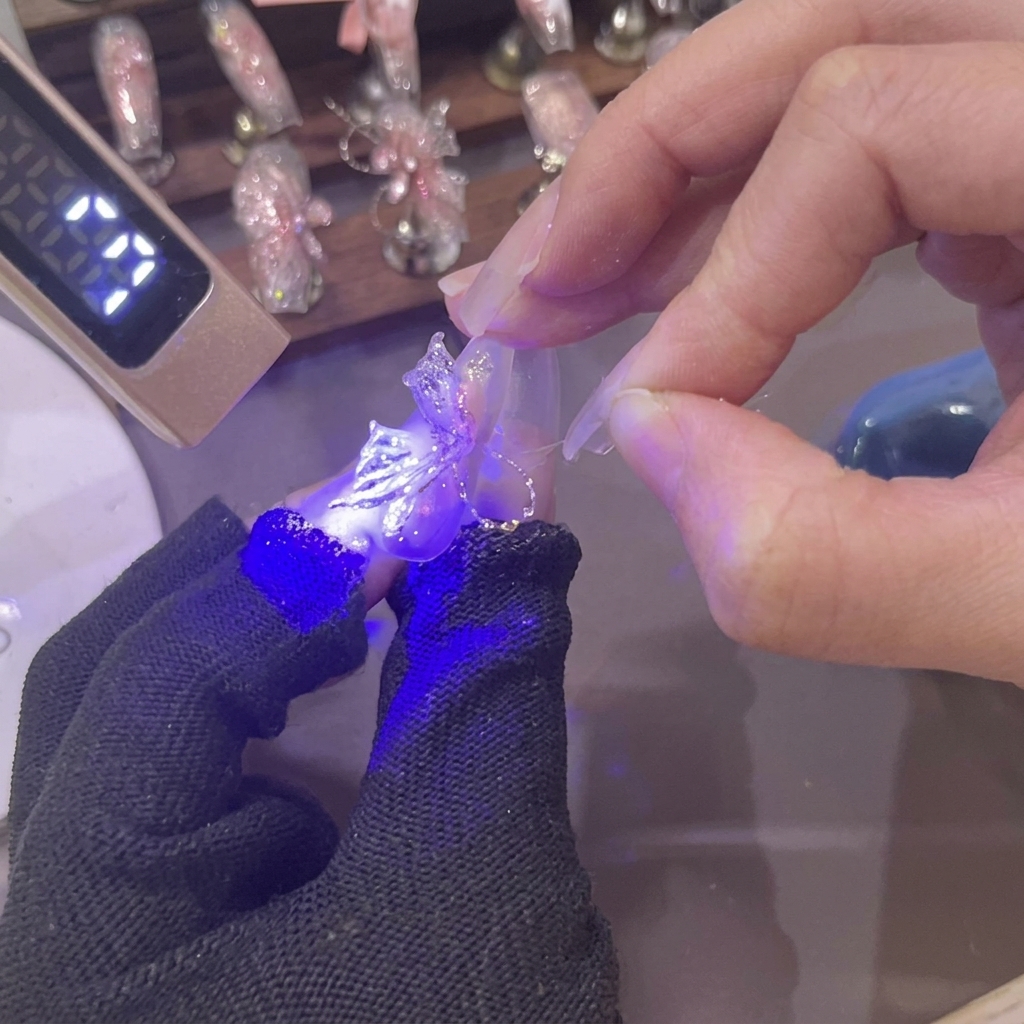 Mini lampa UV świecąca fioletowym światłem na nowo uformowane trójwymiarowe, różowe żelowe skrzydło motyla na paznokciu.
