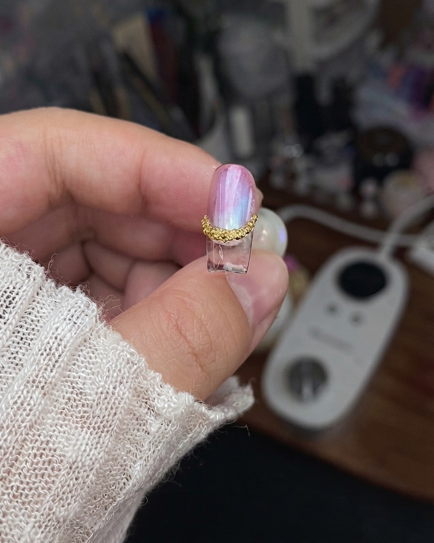 Ein fertiges Nagelstück wird hochgehalten, um die versiegelten Kanten und fertigen Designdetails zu zeigen.