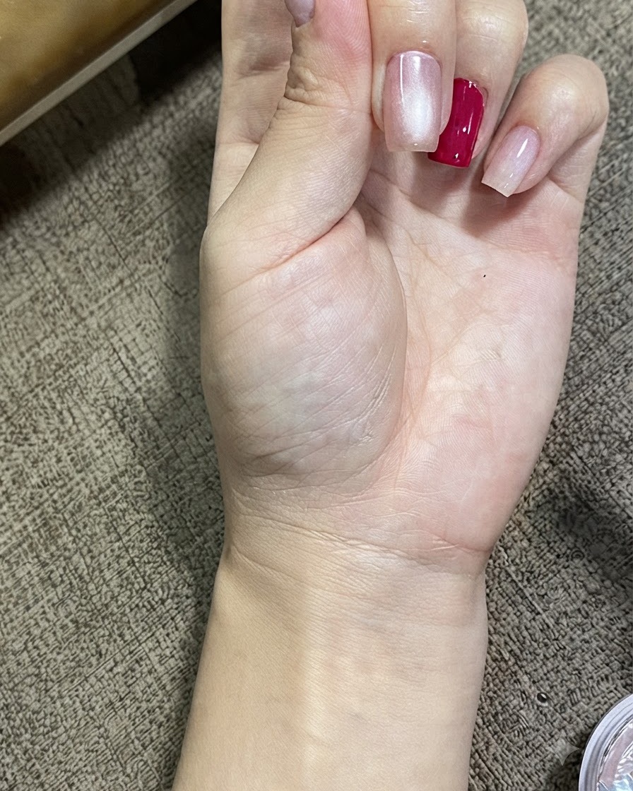 Eine Nahaufnahme einer Hand mit Nägeln, die mit magnetischem Cat-Eye-Gel behandelt wurden, die einen leuchtenden, kugelförmigen Effekt zeigt.
