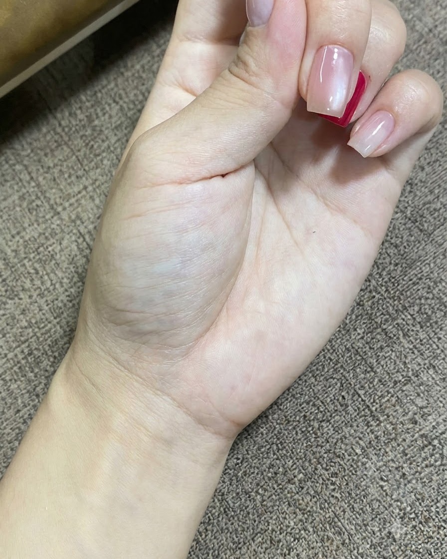 Eine Nahaufnahme einer Hand, die ruht, während eine tragbare UV-LED-Lampe den Gel-Nagellack auf den Nägeln aushärtet.