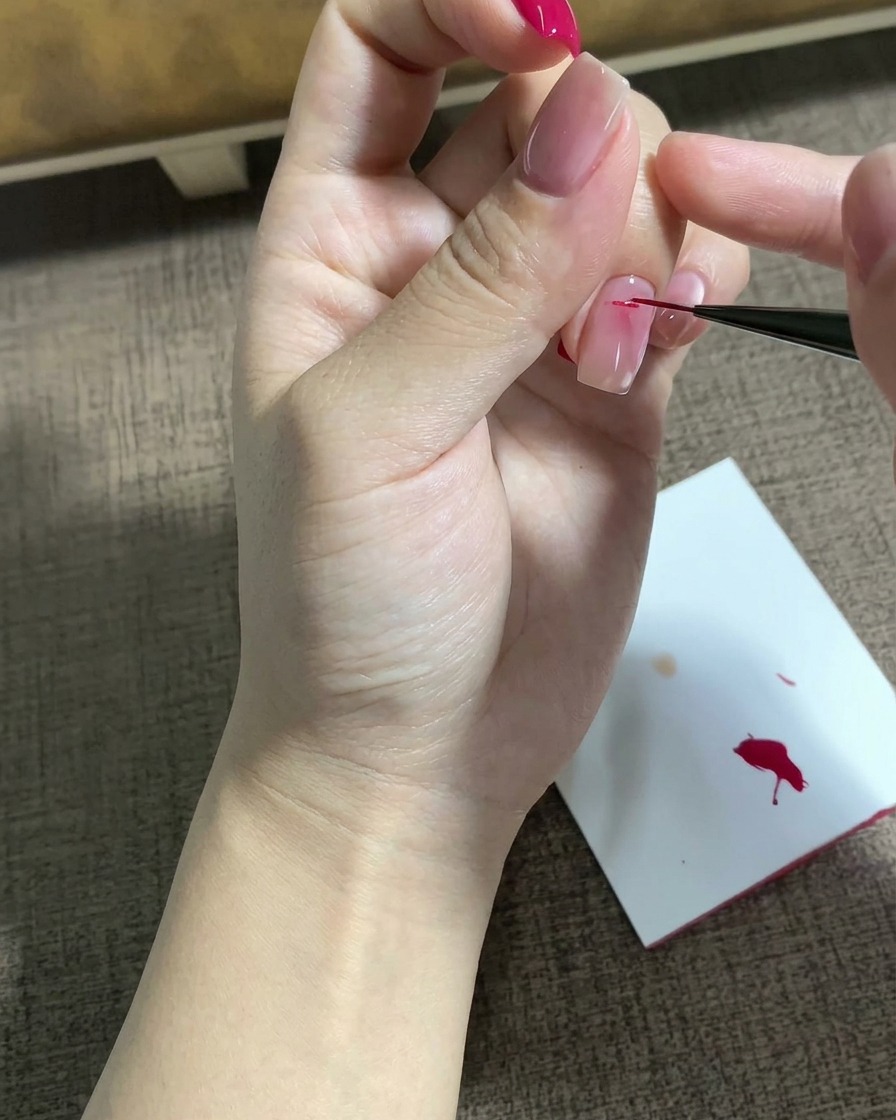 Ein feiner Liner-Pinsel zeichnet ein detailliertes Magenta-Sternmotiv auf eine präparierte Nageloberfläche.