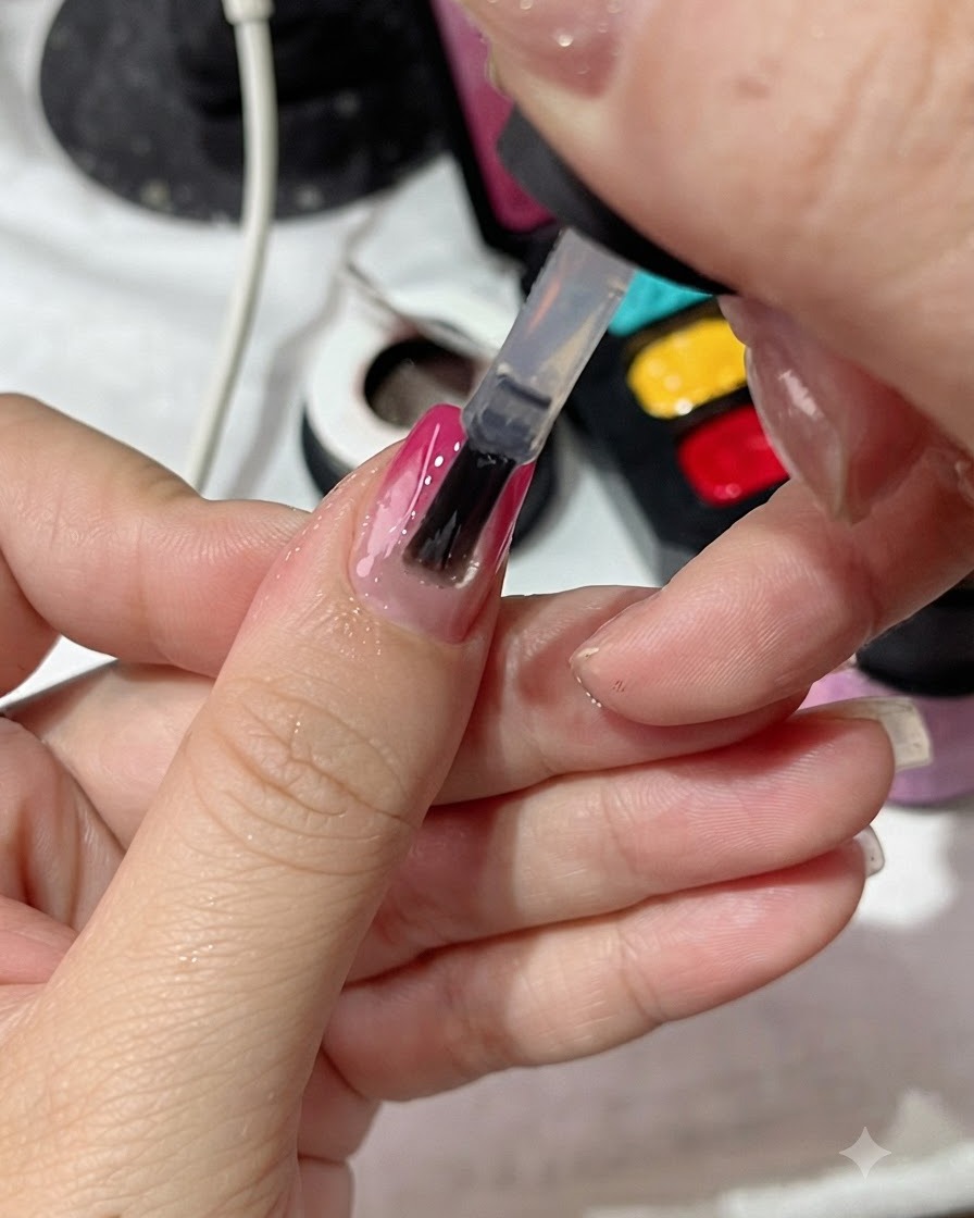 Pędzelek do lakieru nakładający równomiernie przezroczysty top coat na paznokieć z gradientowym manicure.