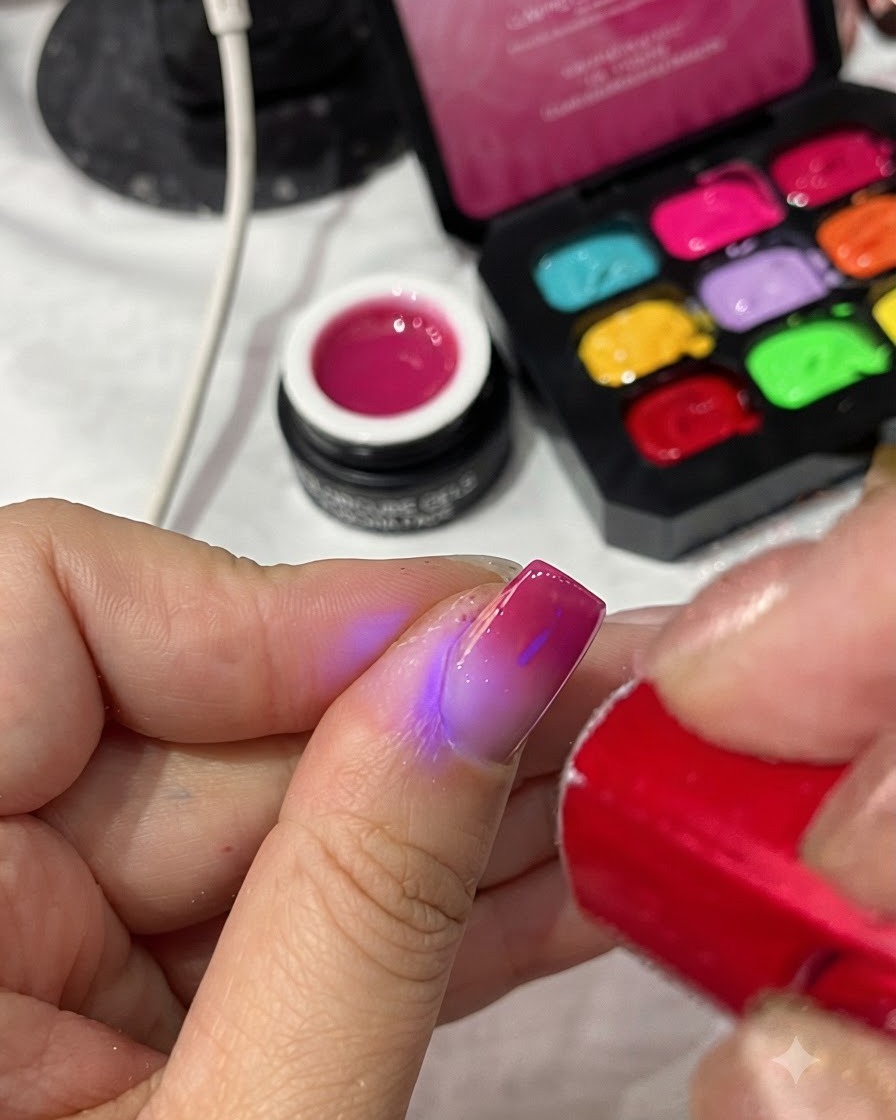 Przenośna czerwona lampa UV/LED utwardzająca top coat na ukończonym manicure.