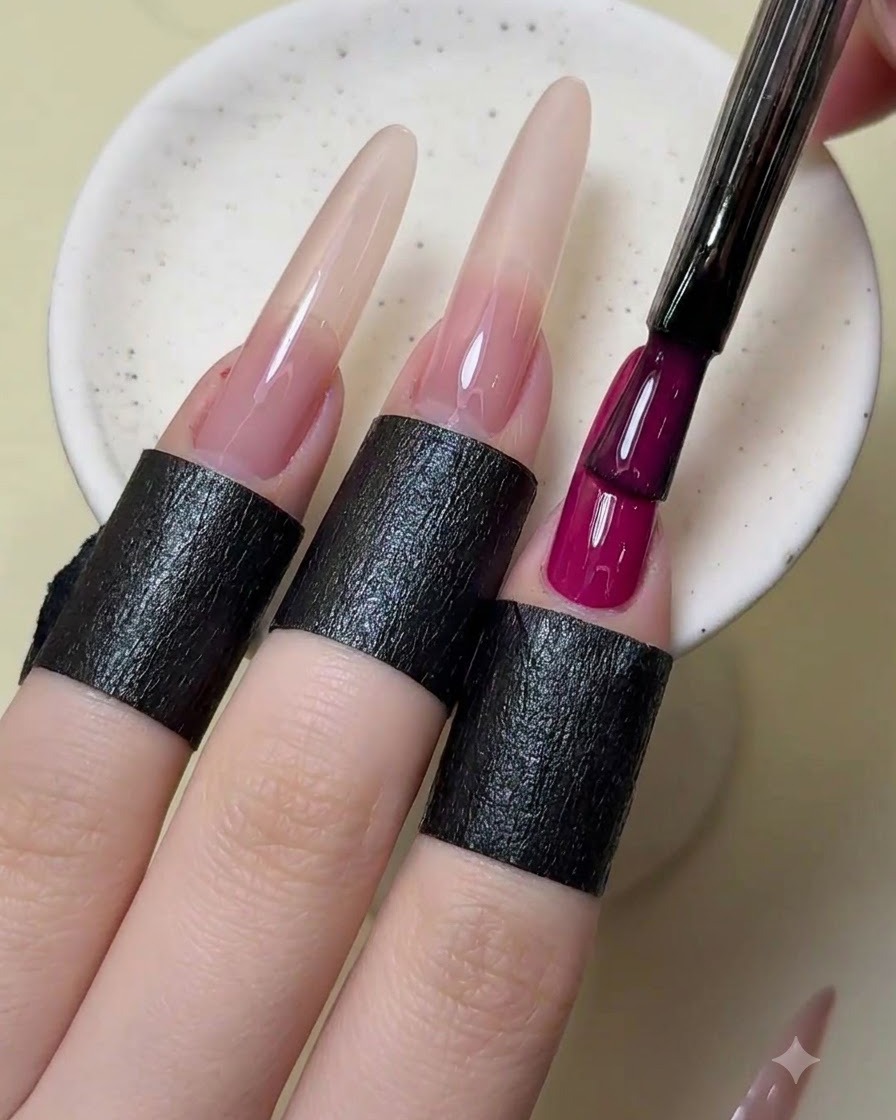 Ein Nagelpinsel fügt dem Zeigefinger eine zweite Schicht opaken magentaroten Lacks hinzu.