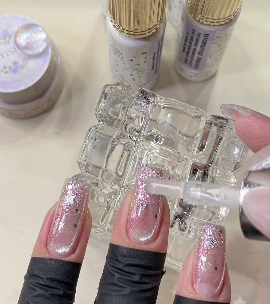 Pędzelek aplikujący ostateczny top coat na ukończone paznokcie w stylu galaktyki.