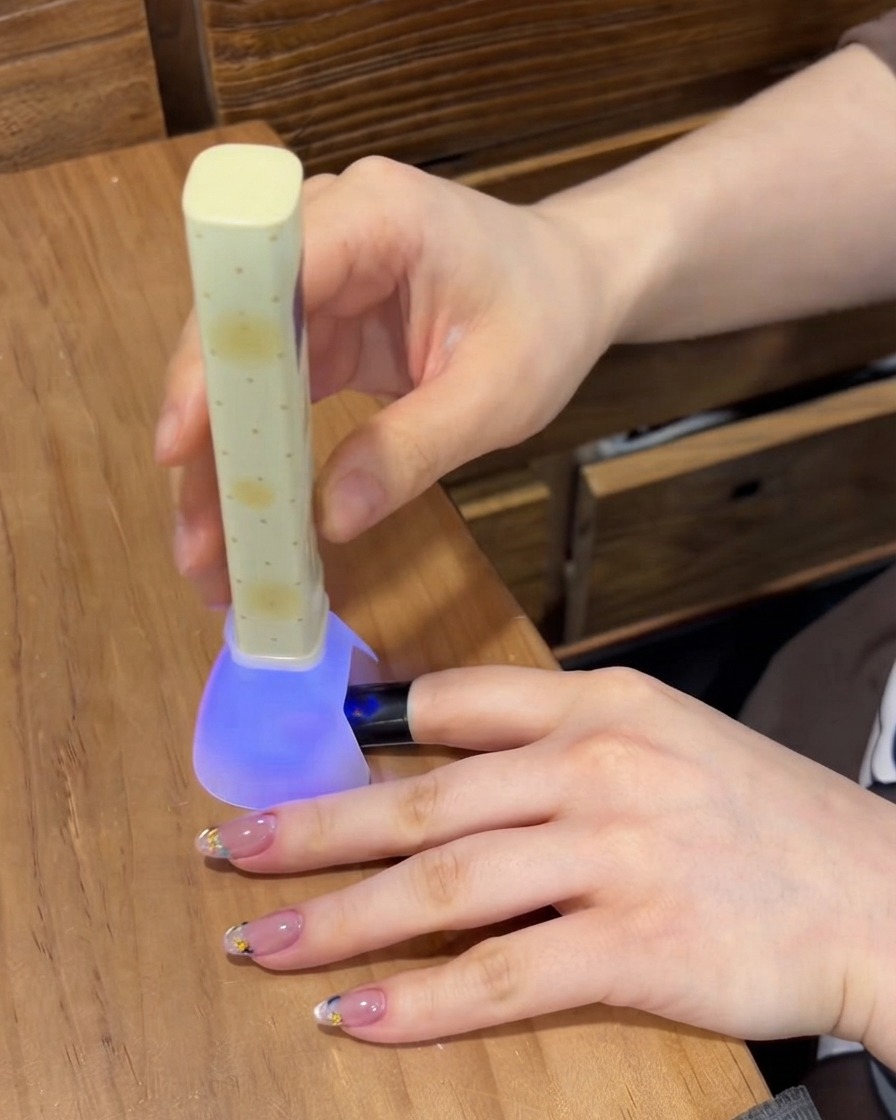 Tragbare UV- und LED-Nagellampe, die das Gel auf einem Fingernagel aushärtet.