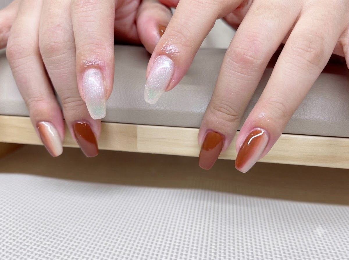 Zbliżenie dłoni ukazujące karmelowo-bursztynowy manicure z lśniącymi liniami efektu cat eye.