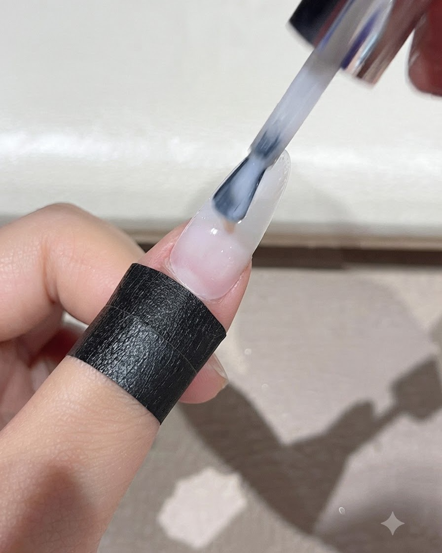 Ein Pinsel verteilt milchweißes, selbstnivellierendes Gel gleichmäßig über die gesamte Nageloberfläche.