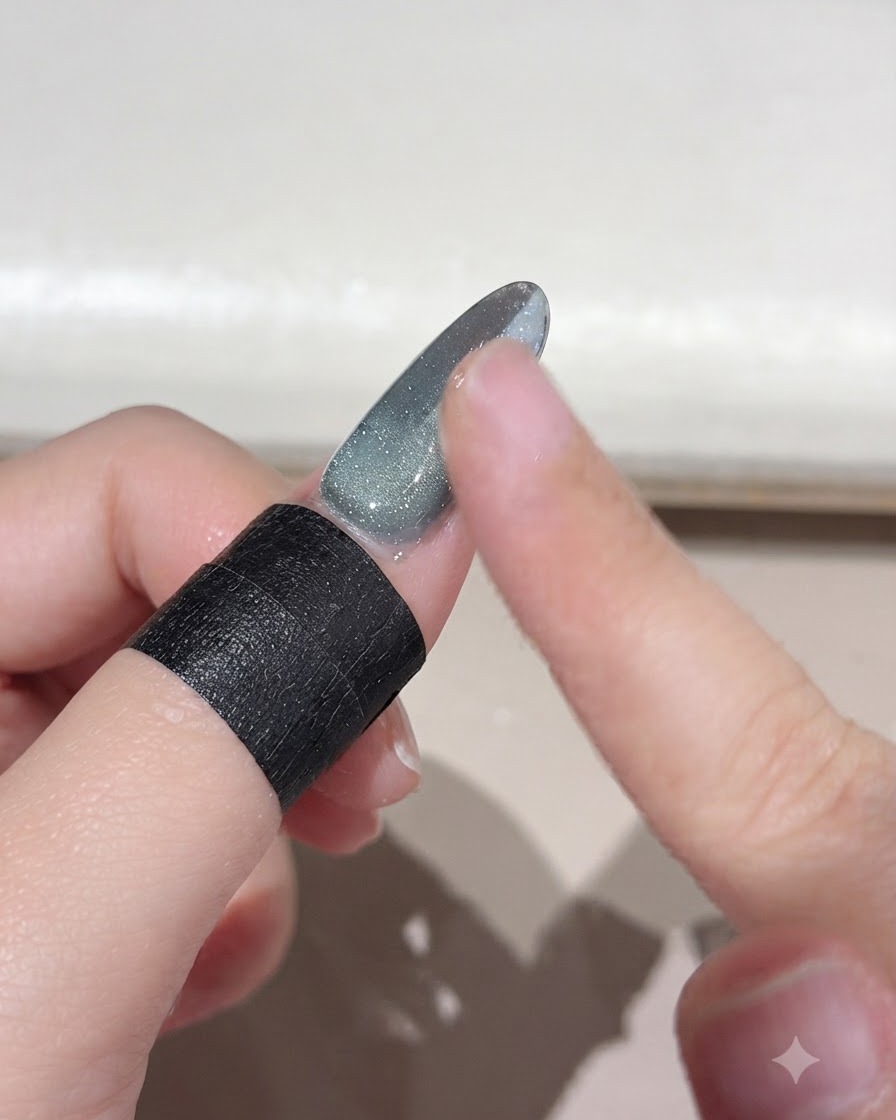 Ein Finger wischt überschüssiges, lose Magiepulver von einer Nageloberfläche mit Farbverlauf ab.