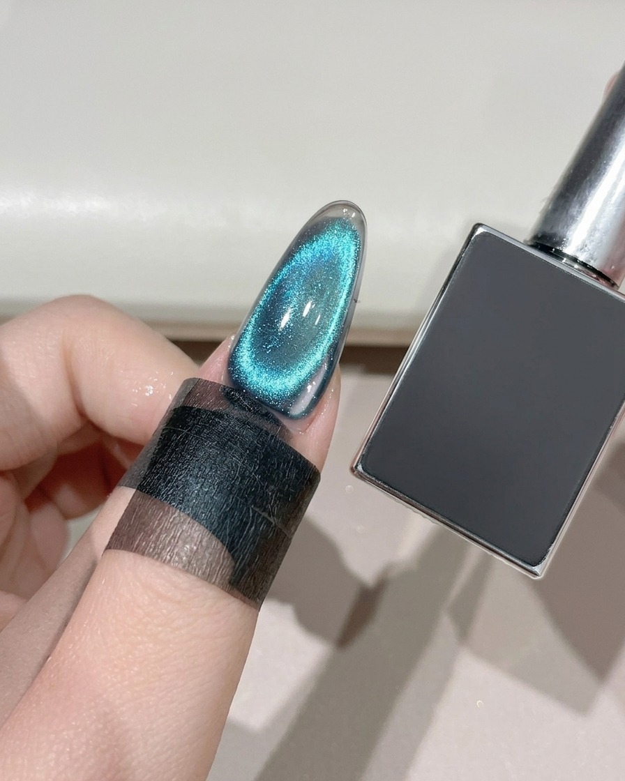 Ein fertiger Cat-Eye-Nagel wird unter einer UV/LED-Lampe neben einer dunklen Gelflasche ausgehärtet.