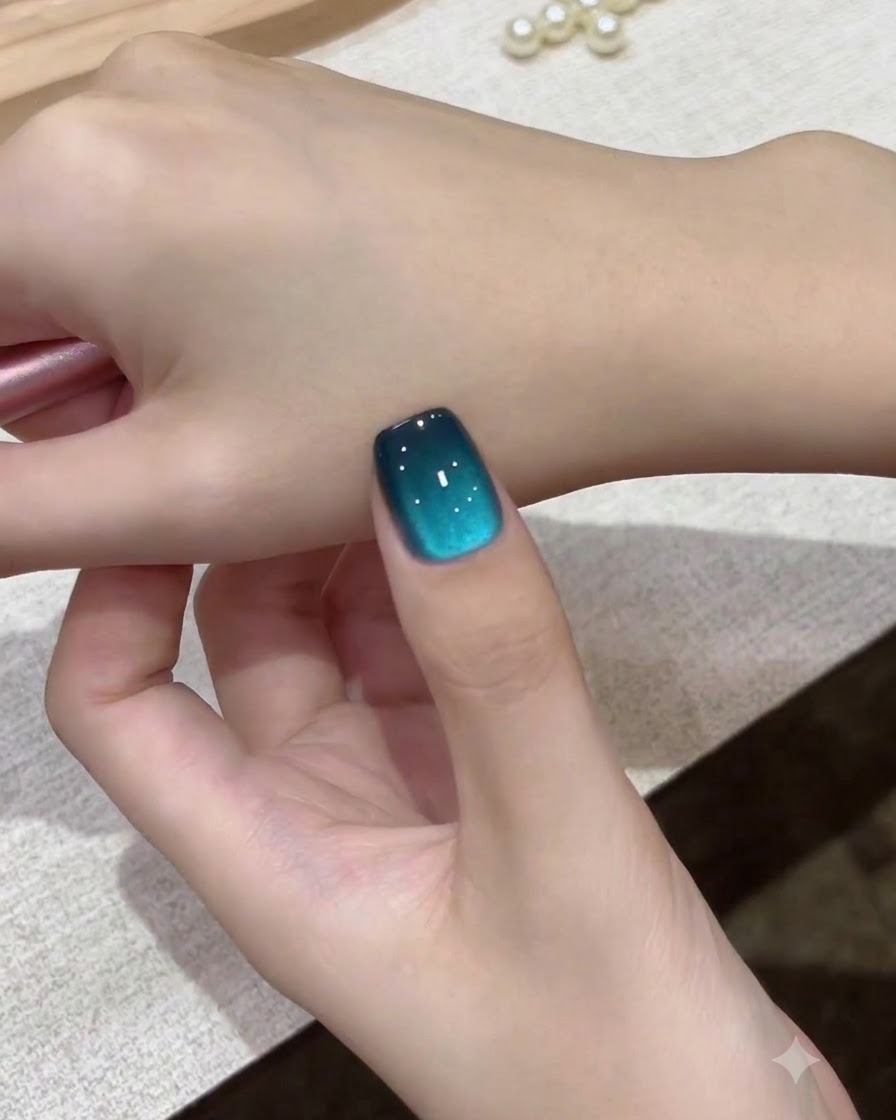 Zbliżenie na pojedynczy, morski paznokieć galaxy cat-eye przyłożony do wierzchu dłoni.