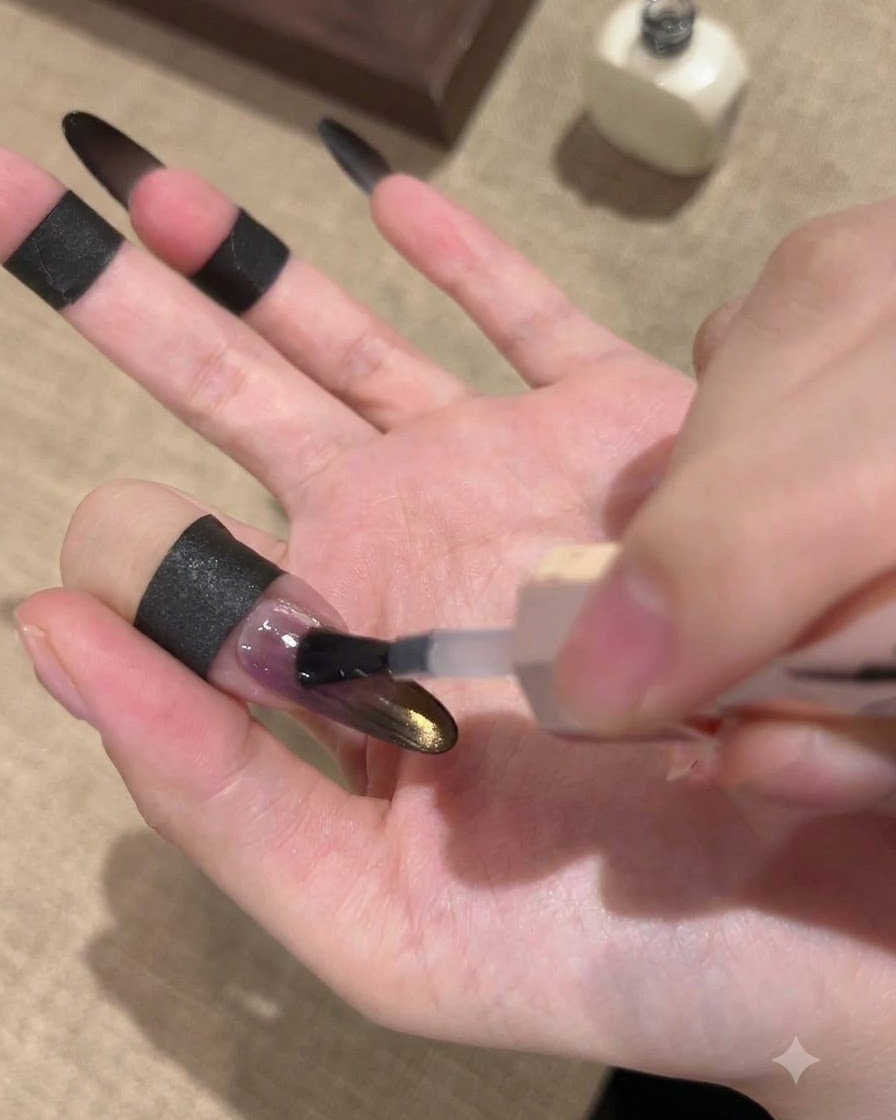 Pędzelek nakładający błyszczący top coat uszczelniający na czarny i złoty paznokieć gradientowy cat-eye.