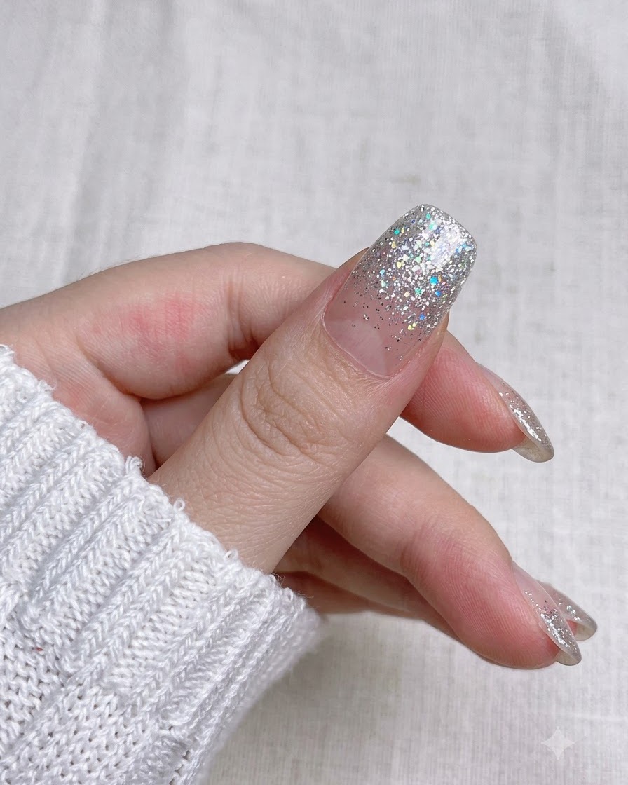Zbliżenie przedstawiające przycinanie nadmiarowego paska naklejki wzdłuż końcówki za pomocą małych nożyczek do manicure.
