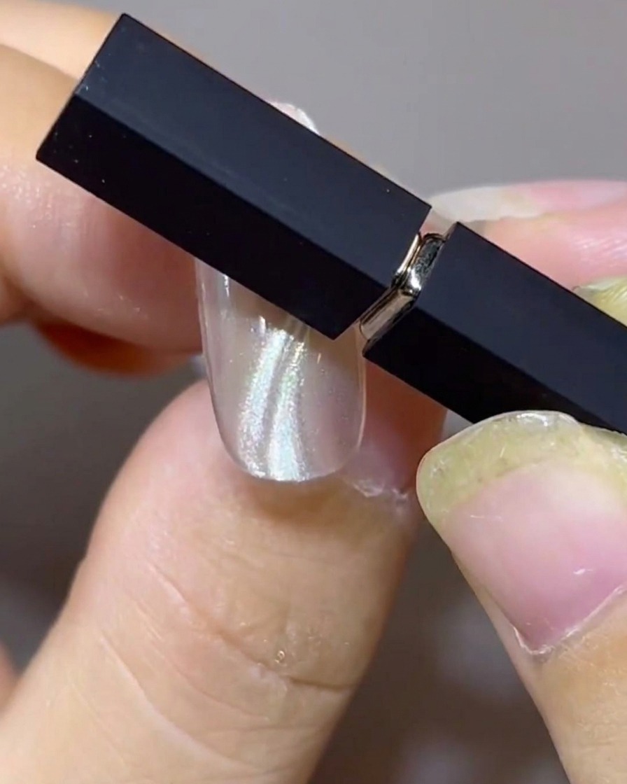 Dwa magnesy ułożone pod kątem nad paznokciem, kształtujące równoległe, podwójne wiszące pasma cat-eye.