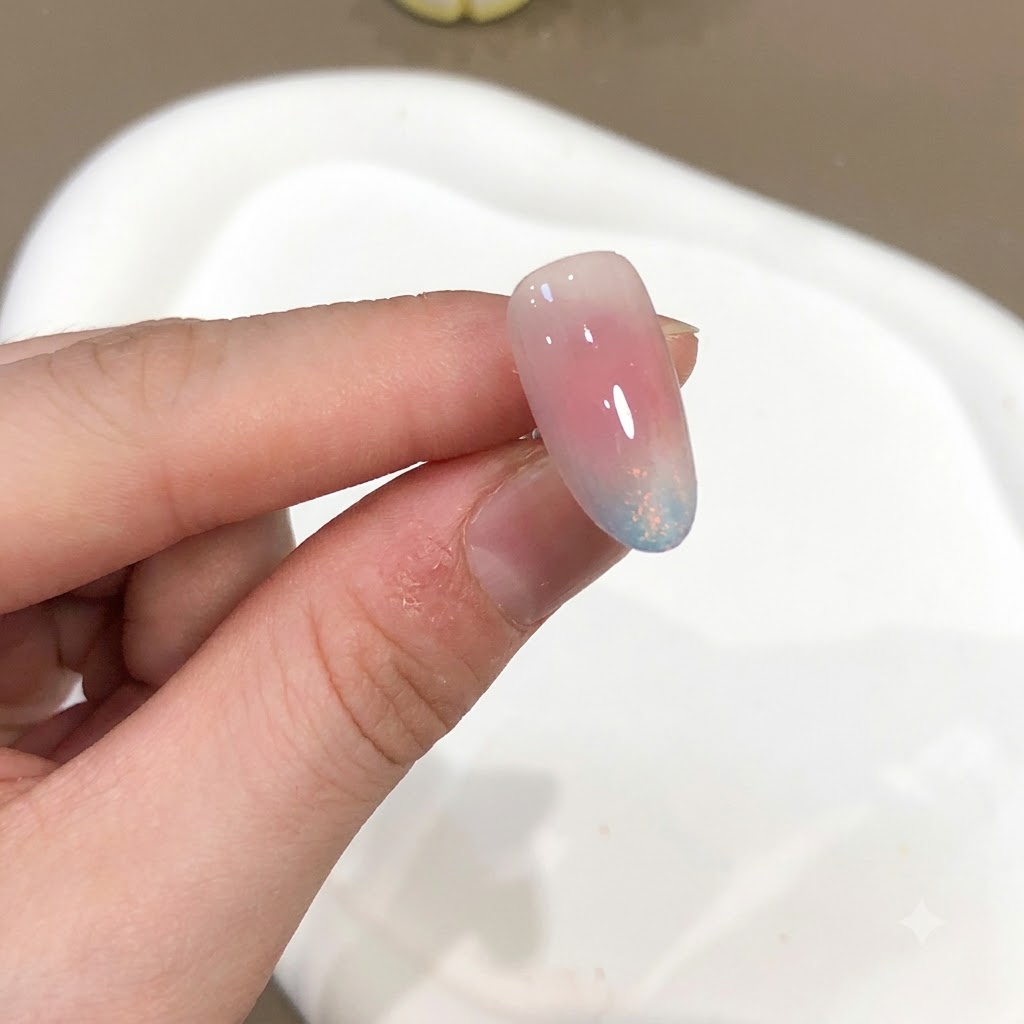 Eine Nahaufnahme eines Nagels mit Rosa- und Blau-Aurora-Puder-Effekt und Hochglanz-Finish.