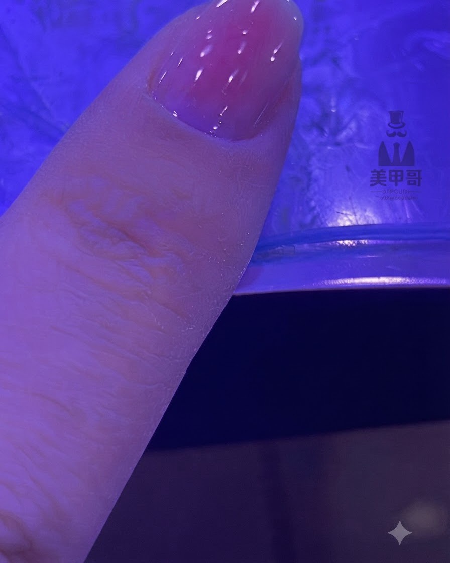 Paznokieć z rozmytym różowym gradientem utwardzający się pod lampą UV/LED.