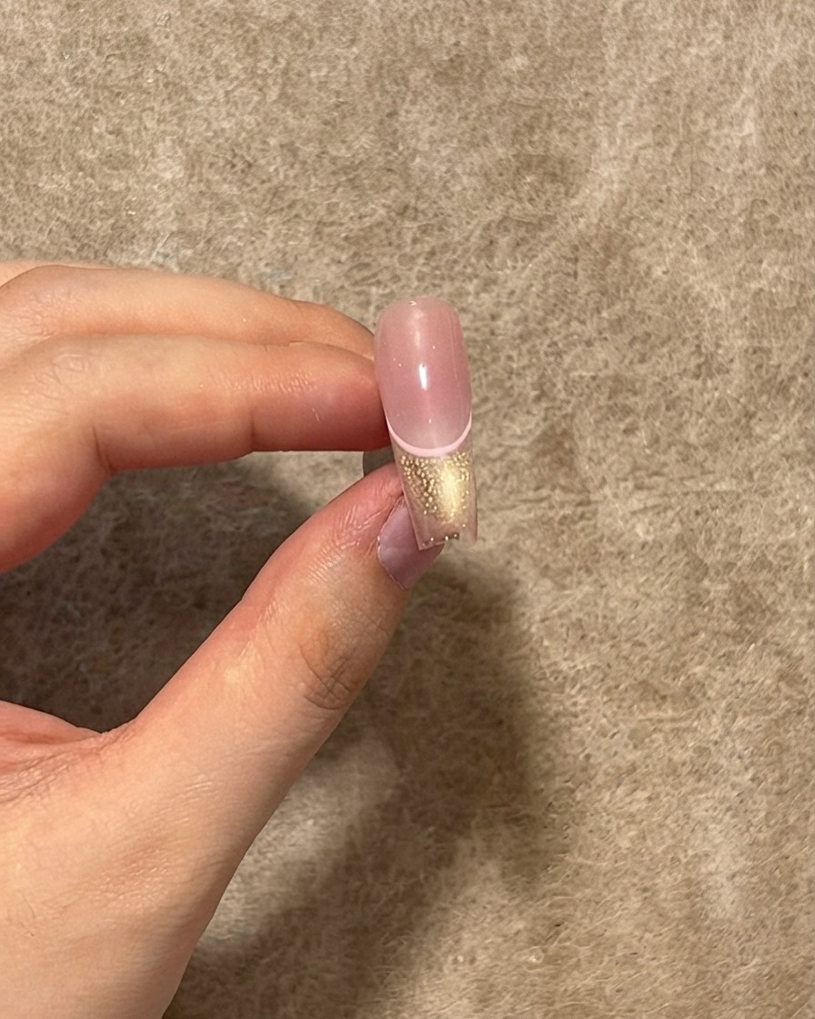 Wykończony paznokieć pokazujący warstwę błyszczącego top coatu nałożonego na różową linię, końcówkę cat eye i środek blush.