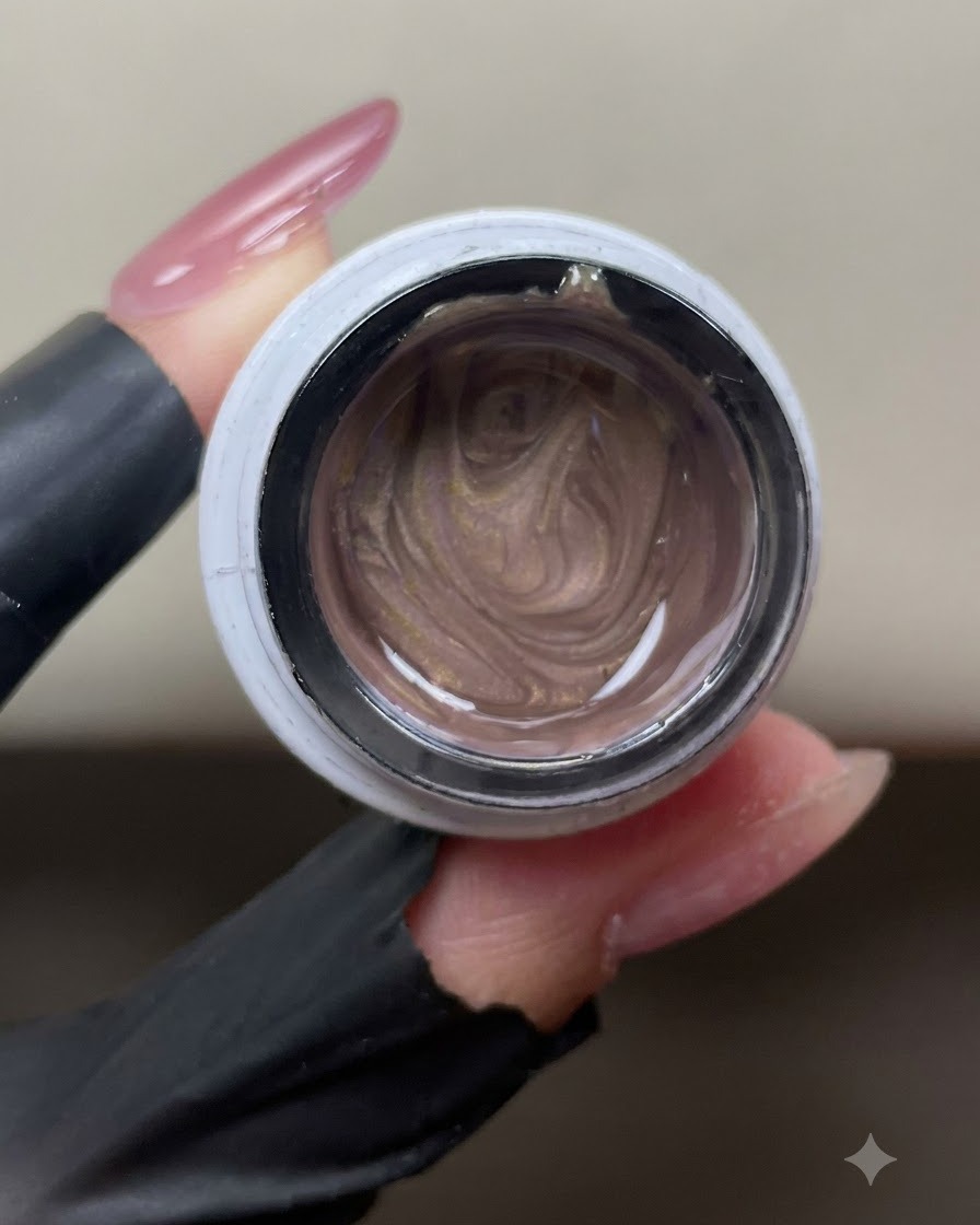 Otwarty słoiczek lśniącego różowo-złotego żelu cat-eye pokazujący wirujące metaliczne cząstki magnetyczne w środku.