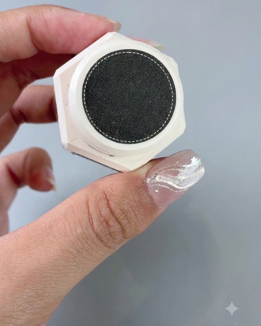 Ein Behälter mit Textur-Styling-Gel wird neben einem Nagel mit angebrachtem French-Aufkleber gehalten.