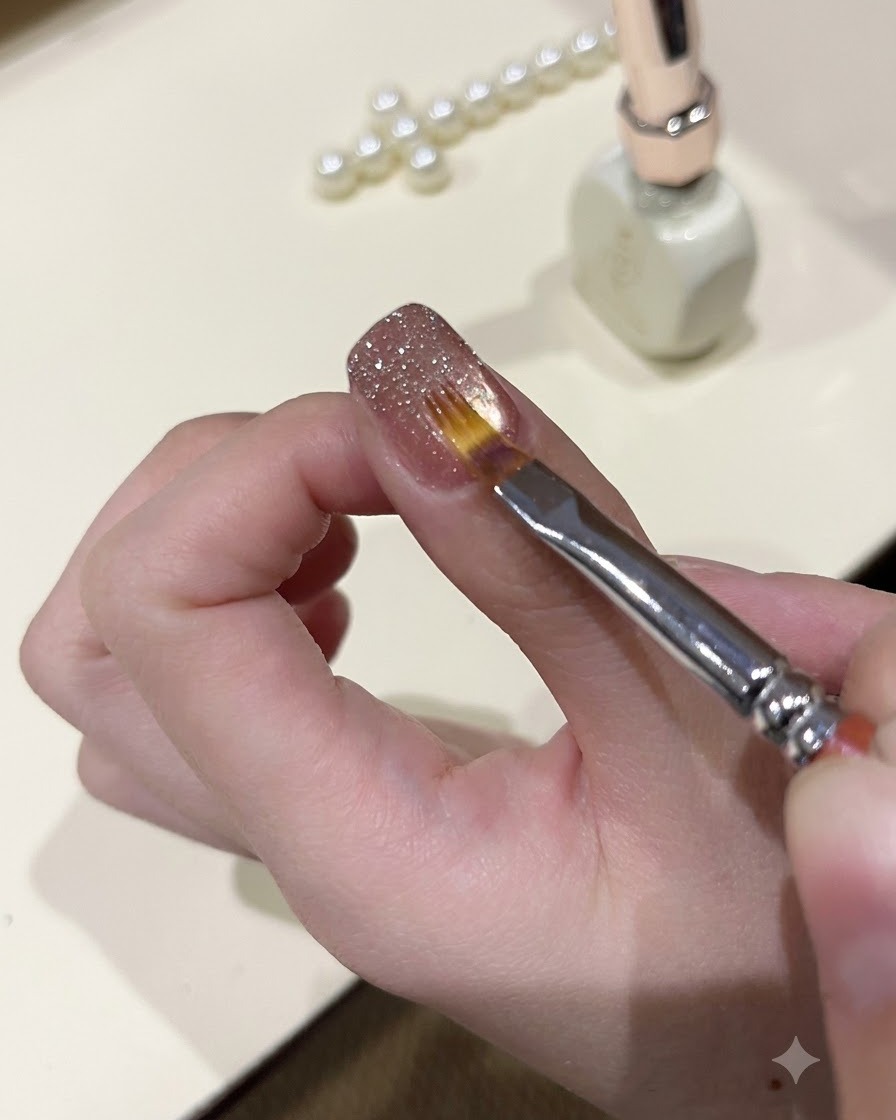 Cienki pędzelek wygładzający błyszczący żel brokatowy na powierzchni manicure.