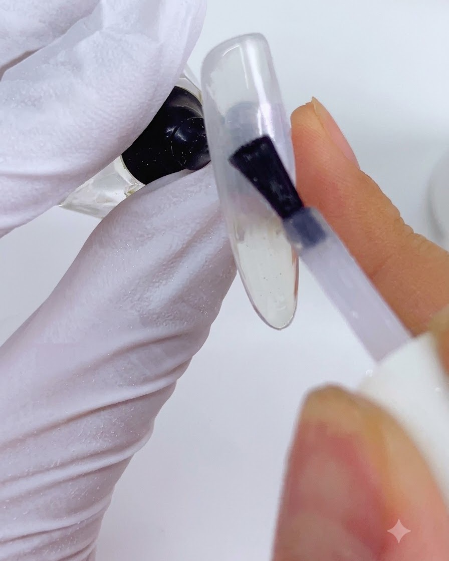 Aplikator nanoszący perłowy pyłek LP02 na pomarańczowe sekcje projektu paznokcia.