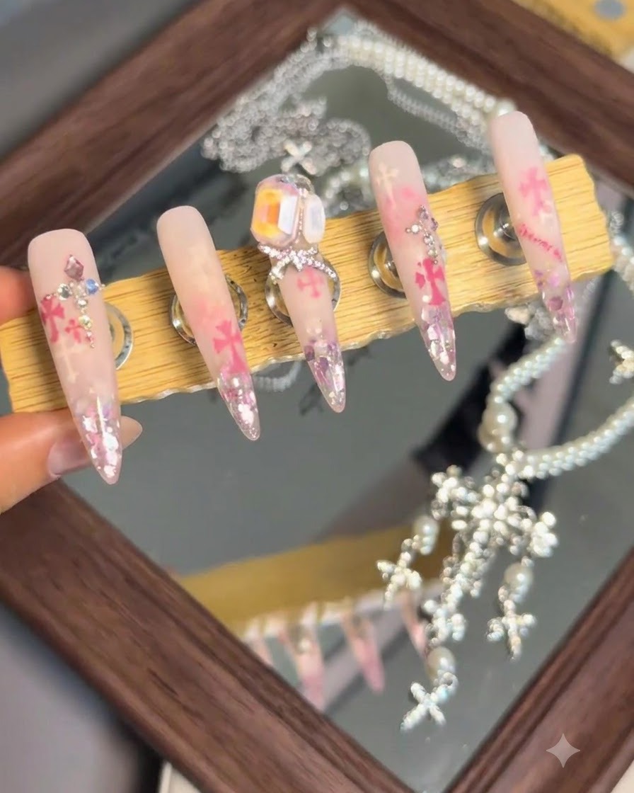 Stojak ekspozycyjny pokazujący zestaw gotowych elementów nail art z wybitnym dużym kryształem i ozdobą z kokardką na środkowym paznokciu.