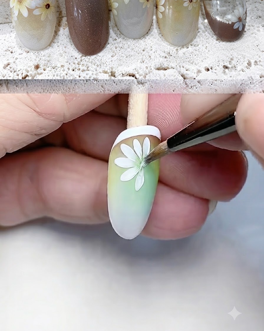Cienki pędzelek starannie malujący i definiujący białe płatki margaritki na tipsie z gradientem.