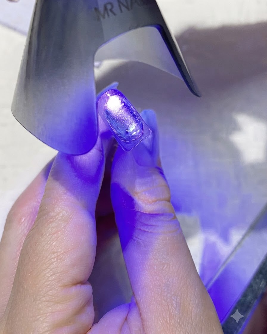 Mini fioletowa, ręczna lampa UV/LED emitująca fioletowe światło bezpośrednio nad powleczonym paznokciem.