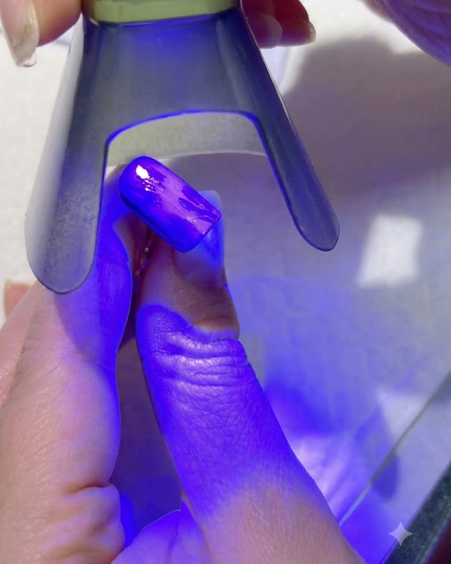Fioletowa lampa UV utwardzająca jasnozielone detale liści na malowanym paznokciu.
