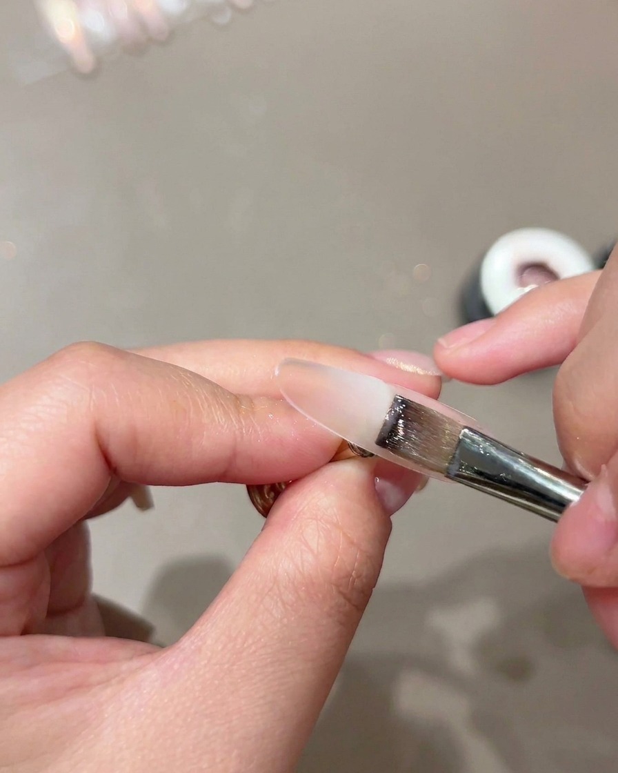 Plochý štetec aplikujúci priesvitnú telovú podkladovú vrstvu na šablónu nechta.