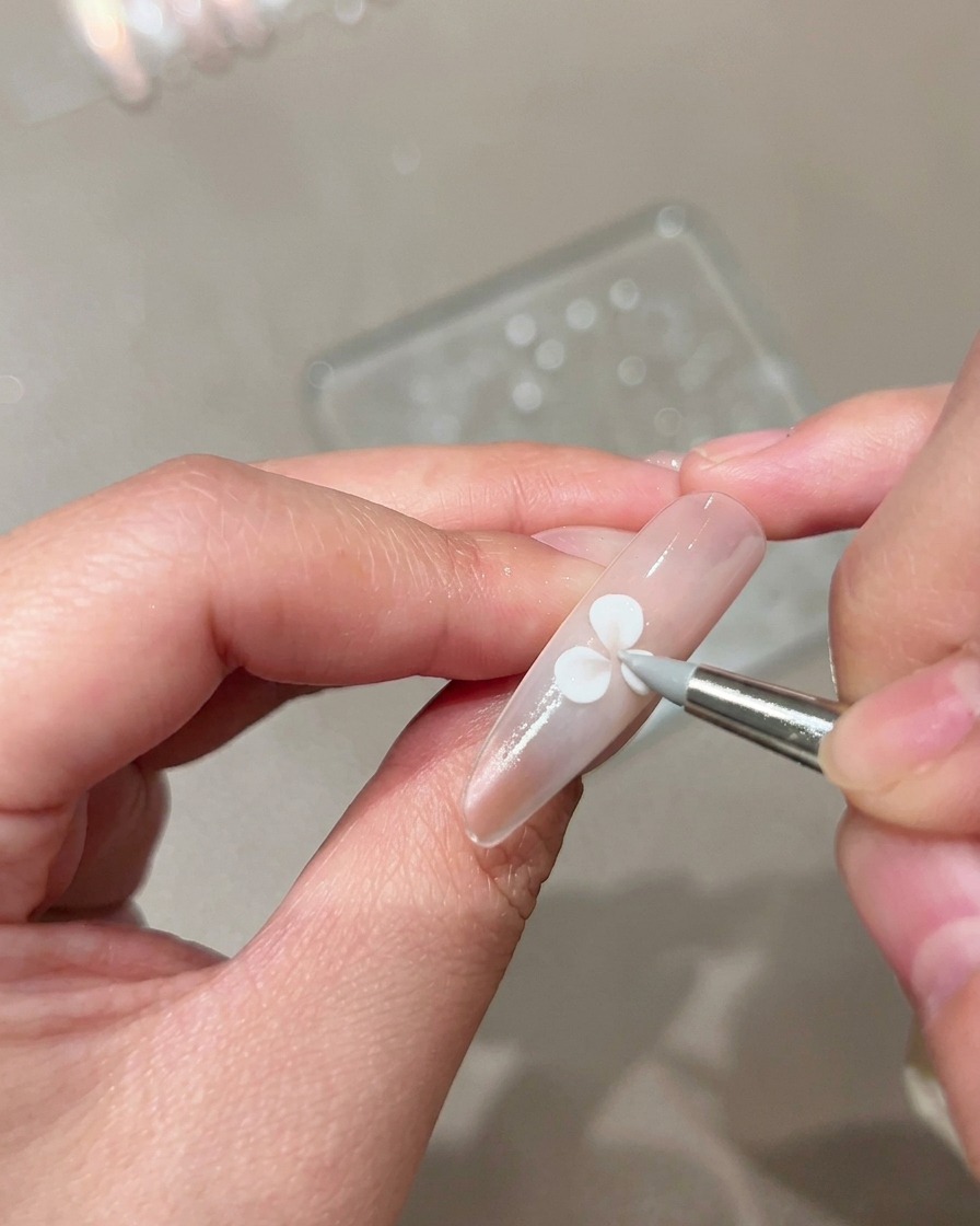 Silikónový modelovací štetec stláčajúci a tvarujúci biely gélový lupienok na upravenom telovom nechte.
