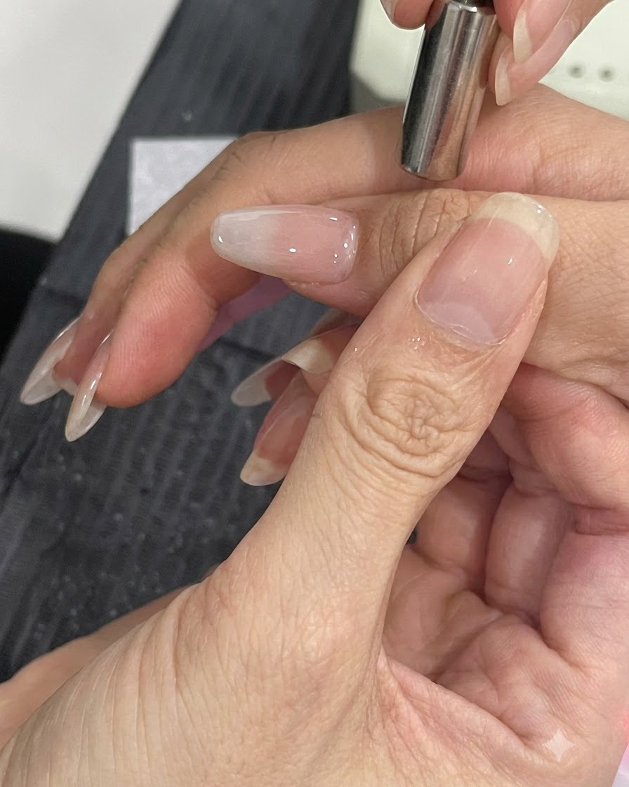 Mały magnes trzymany blisko boku wypielęgnowanego paznokcia w celu przesunięcia cząsteczek połysku cat-eye.