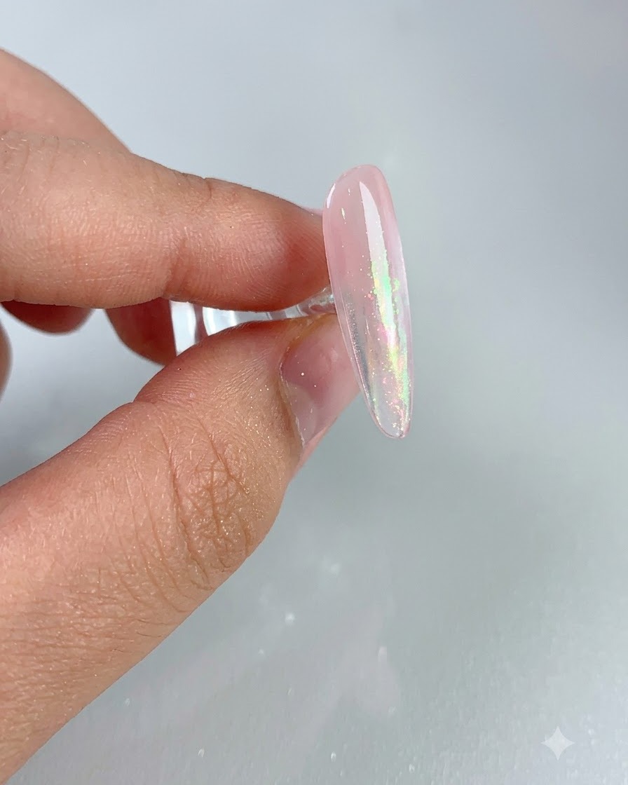 Eine Nahaufnahme eines glänzenden rosa Nagels mit schimmertem Aurora-Effekt nach dem Abkehren überschüssigen Puders.