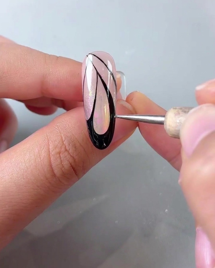 Ein Dotting-Pen setzt kleine weiße Punkte entlang des Außenrandes der schwarzen Schmetterlingsflügel-Nail-Art.