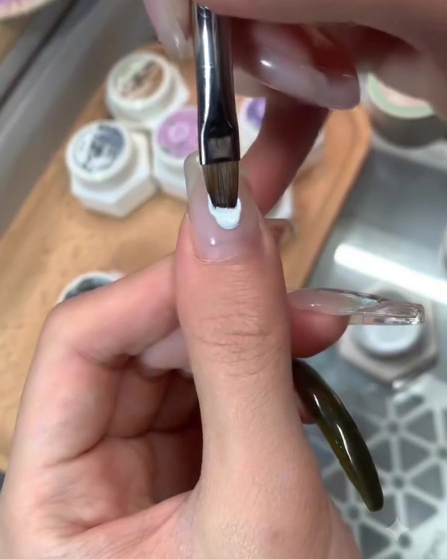 Pędzelek nakładający błyszczący top na wykończony niebieski nail art.