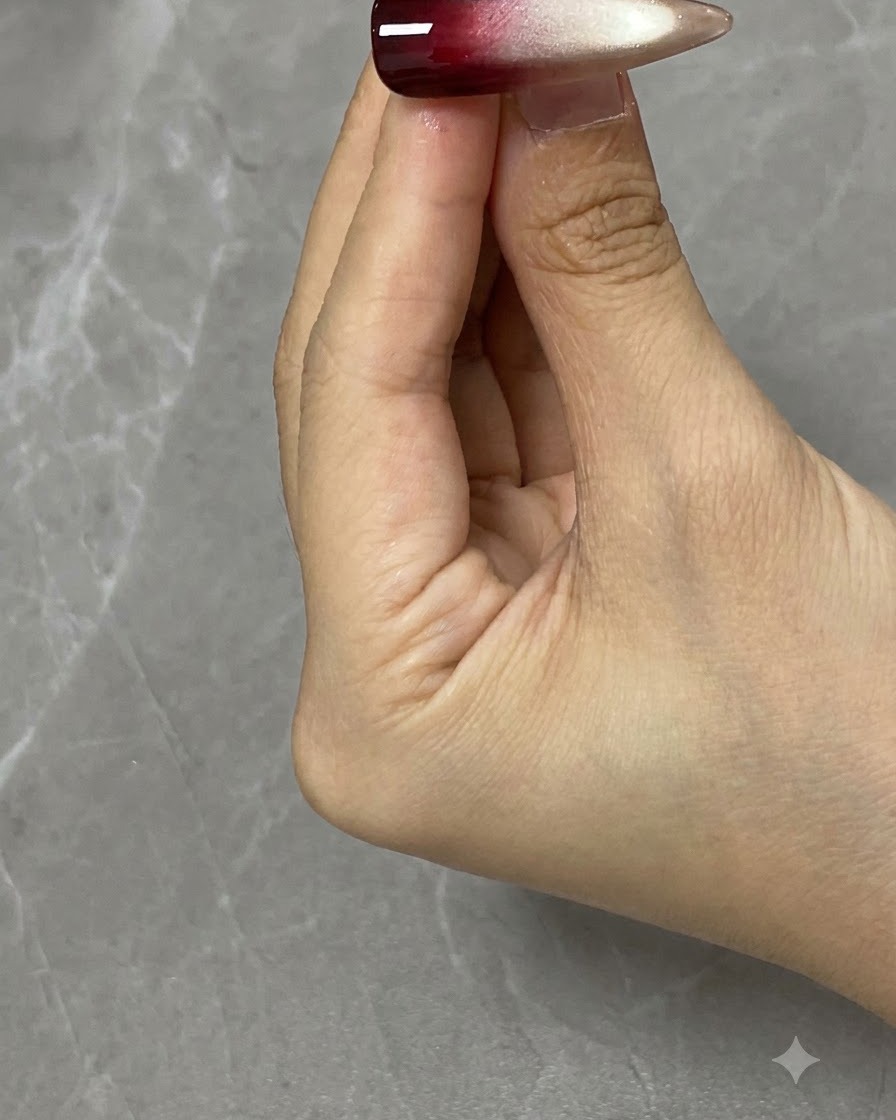 Pędzelek do nail art nakładający transparentny czerwony żel na górną połowę ozdobionego paznokcia.